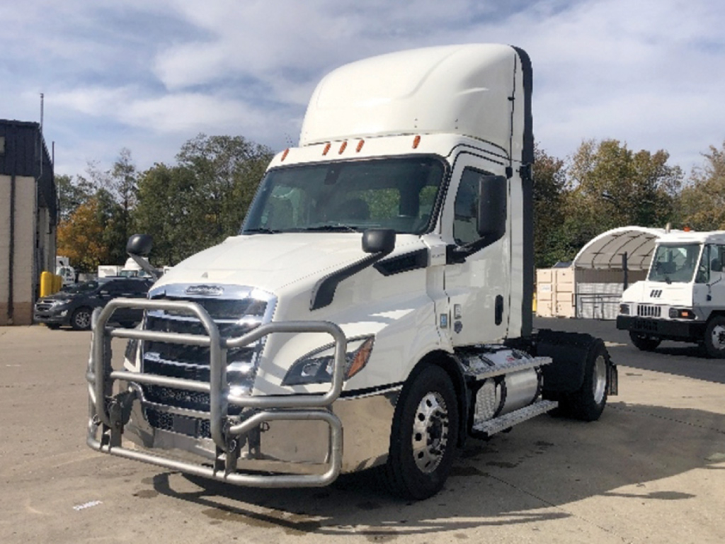 Truck front-quarter view of a white Freightliner Cascadia 116 with a grille guard. Visible text on the truck includes no legible model or branding details in close-up. 