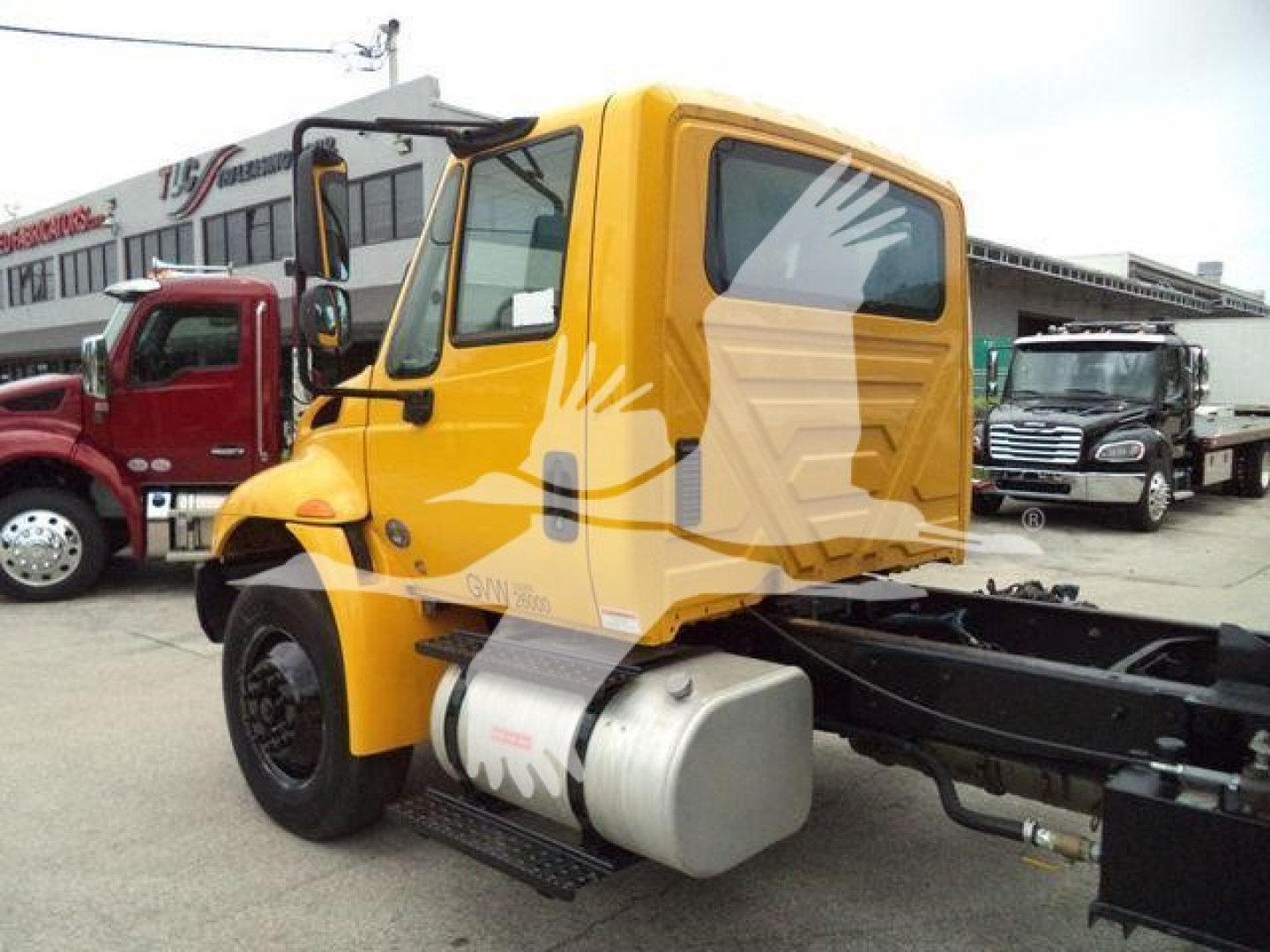 Truck cab of a yellow 2019 International 4300 dump truck with VIN 3HAMMMML2KL383586 and stock number T83586 visible in listing; side fuel tank and chassis components show.