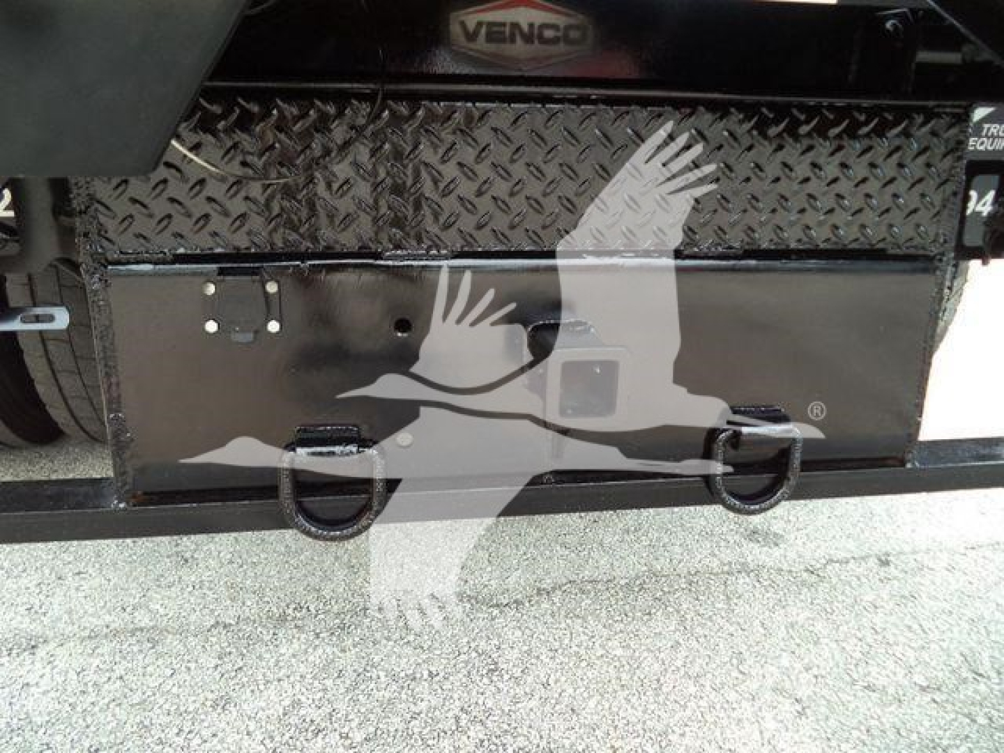 Storage toolbox and rear bumper on a 2019 International 4300 dump truck viewed from rear showing diamond tread toolbox and D-rings.