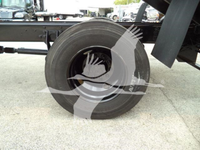 Dump truck chassis showing spare tire mounted on rim and undercarriage components.
