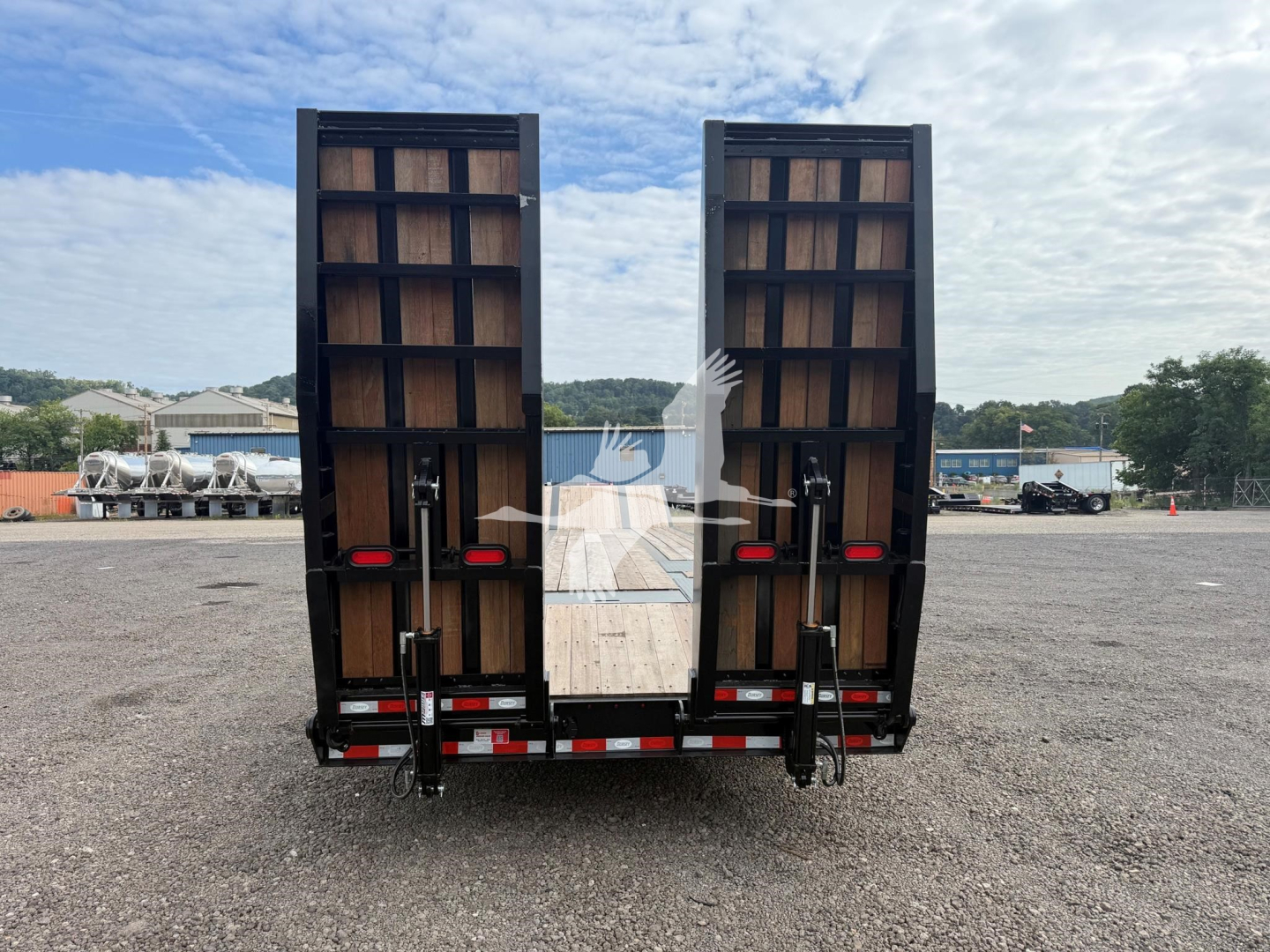 Trailer backsides with split rear ramps on a drop deck trailer showing wooden deck and hydraulic ramps.