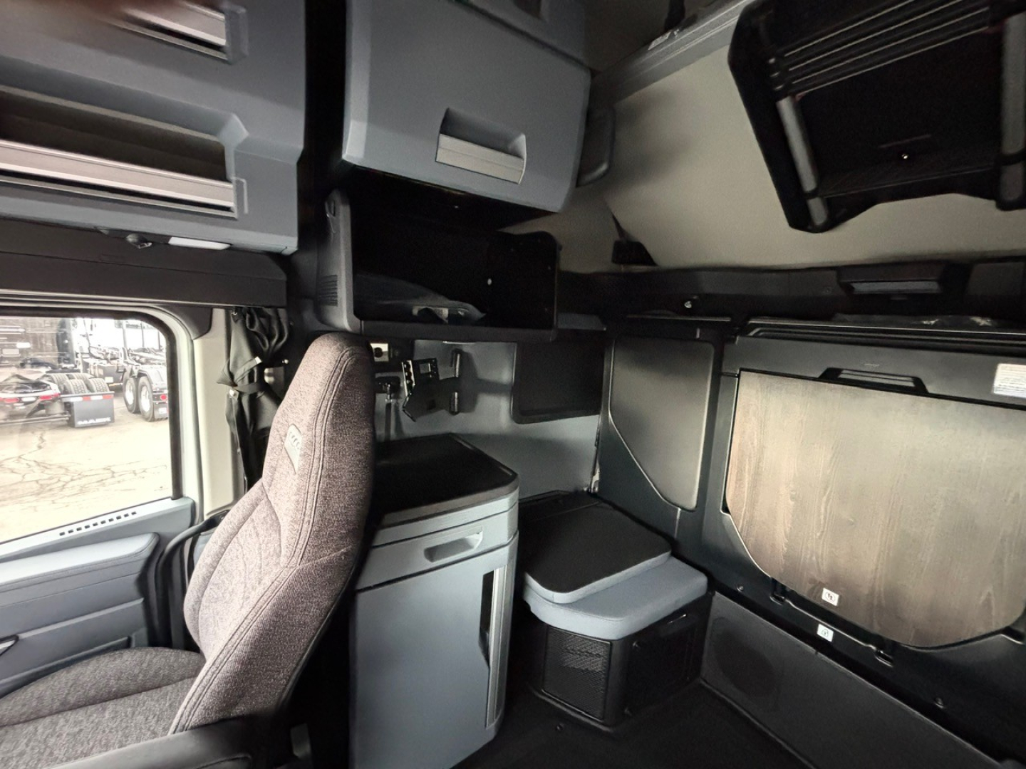 Cab interior of a 2026 Mack PR64T76H truck showing driver seat and overhead storage compartments.