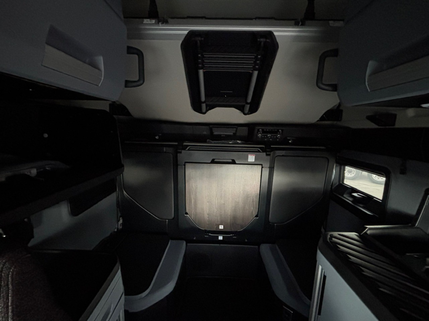 Cab interior of a 2026 Mack PR64T76H sleeper cab showing cabinetry and step well. Visible text includes VIN and stock, though not legible due to interior lighting.
