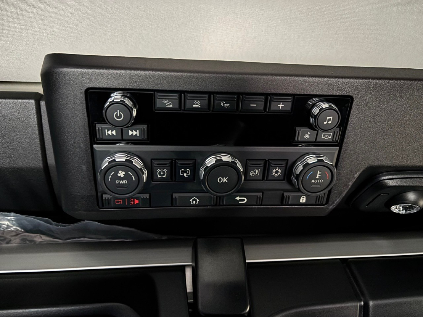 Dashboard control panel of a new Mack PR64T76H truck showing climate and media controls with knobs and buttons.