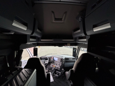 Cab interior view of a modern Mack PR64T76H truck sleeper cab showing dashboard with touchscreen display and overhead storage compartments.