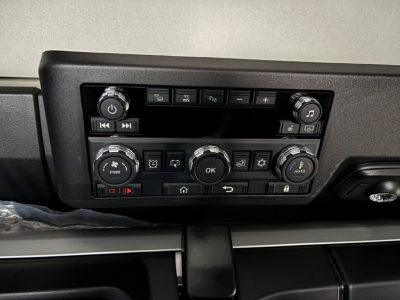 Dashboard control panel of a new Mack PR64T76H truck showing climate and media controls with knobs and buttons.