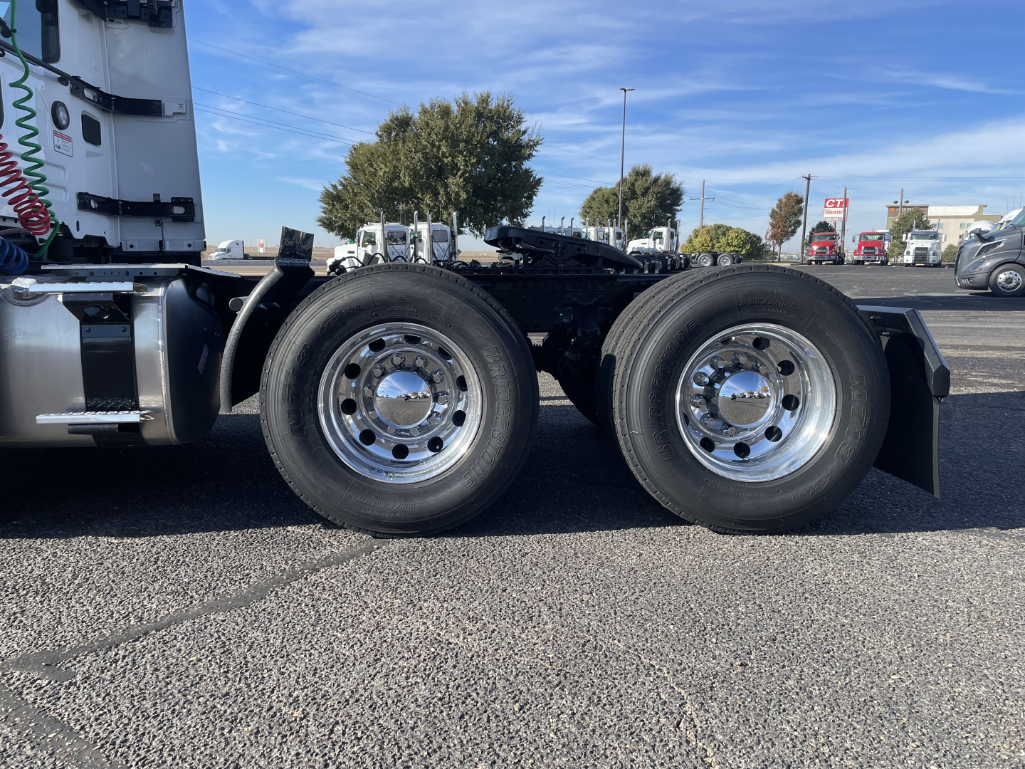 Mack PR64T truck chassis side view showing dual rear axles with polished chrome wheels and tires, cab visible in background.