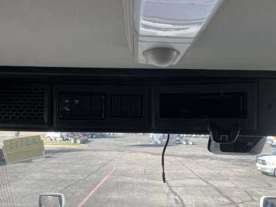 Dashboard area of a 2026 Mack PR64T truck showing a glare-free dash with radio-like panels and a hanging wire.