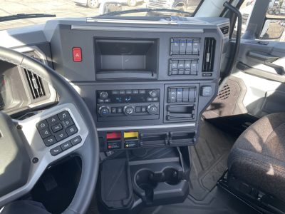 Mack PR64T truck interior dashboard with steering wheel, control panels, climate controls, and storage compartments. visible switches and cup holders.