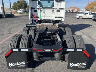 Rear view of a new Mack PR64T conventional daycab tractor showing chassis and tandem rear axles, fifth wheel housing, and Bruckners mudflaps with equipment branding.