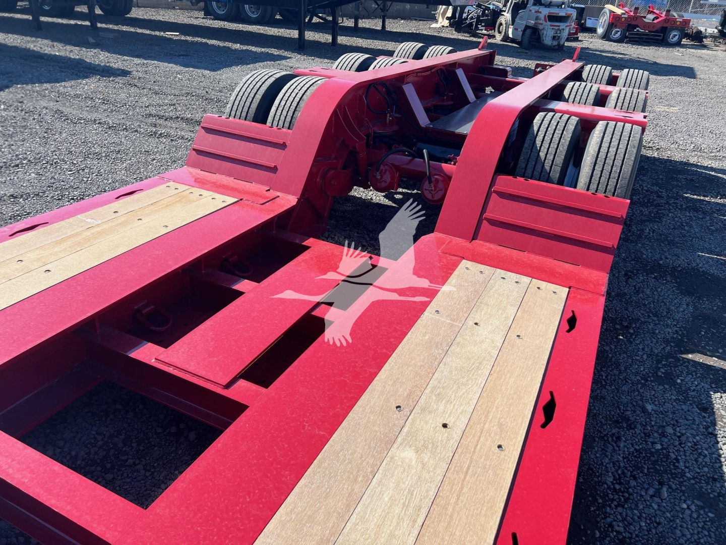 Trailer chassis showing red Fontaine lowboy with wooden deck sections and dual axles, view from rear-left side.