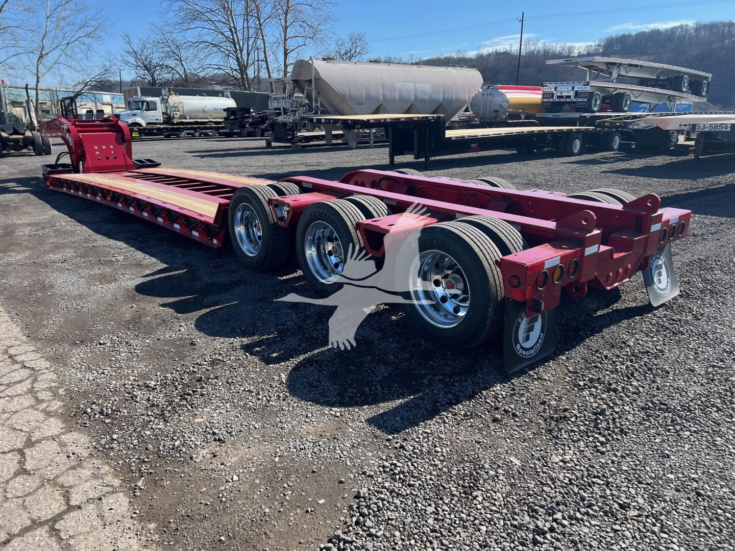 Fontaine 55 Lowboy trailer chassis showing dual rear axles with chrome wheels and red frame.