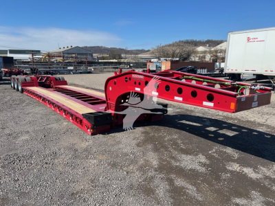 Fontaine lowboy trailer frame showing red structural rails and wheel axles with exposed steel and tubing.