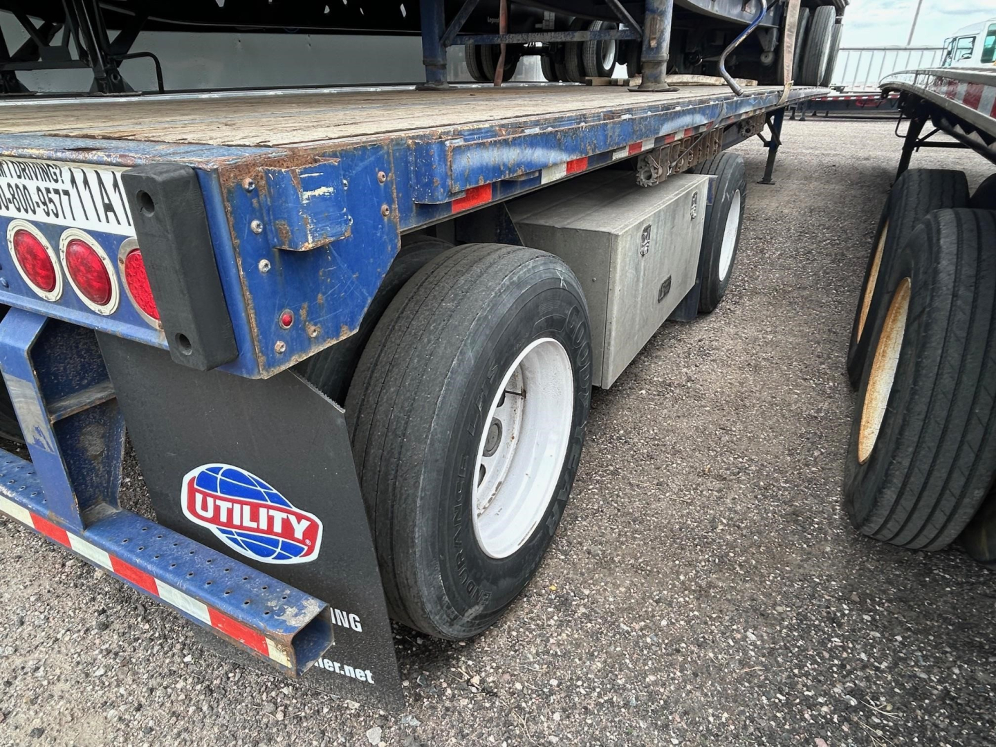 Great Dane steel spread air flatbed trailer showing dual rear axles and mud flaps with Utility sticker and reflective tape.