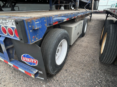 Great Dane steel spread air flatbed trailer showing dual rear axles and mud flaps with Utility sticker and reflective tape.