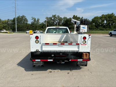 Ford F-350 dump truck bed rear view showing taillights, rear bumper, and dump bed with safety reflectors in a parking lot.