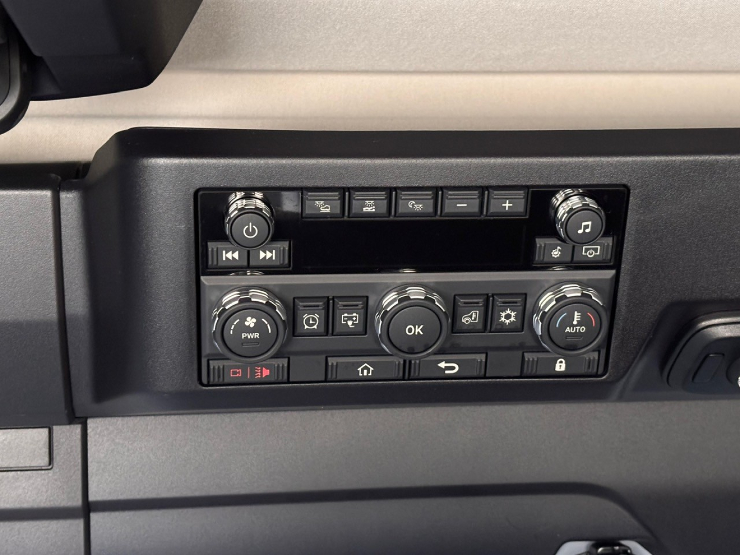 Truck cab panel showing weathered controls including circular dials, buttons, and OK pad; appears in a Mack PR64T76H sleeper truck cabin.