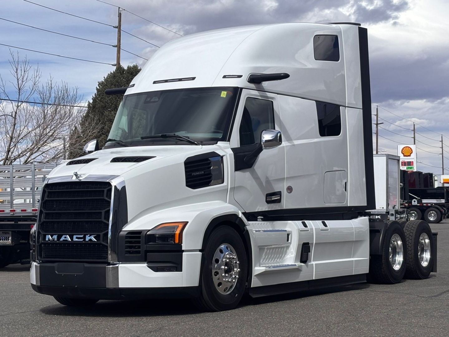 Mack PR64T76H conventional sleeper truck in a dealership lot showing large front grille and white cab with black accents.