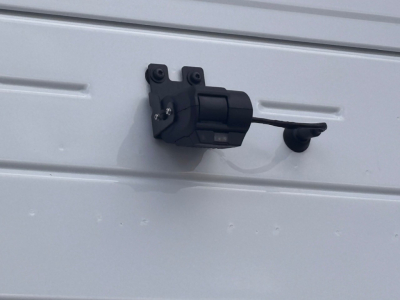 Truck door latch/hinge assembly mounted on a metal surface, view focused on the latch mechanism.