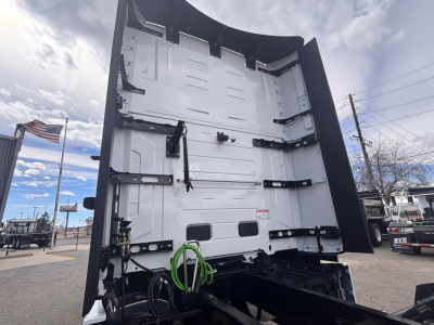 Mack PR64T76H truck rear view showing body with green and black hoses/cables, white interior surfaces, and lift gate area.