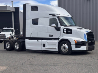 Mack PR64T76H heavy truck in a dealership lot showing side profile of a white sleeper cab with black grille and chrome mirrors.