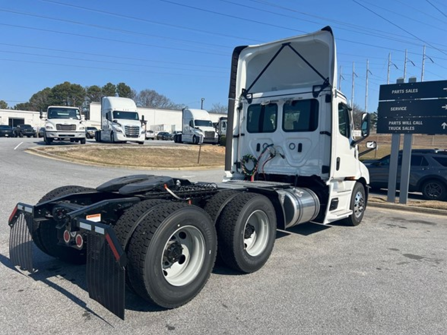 Freightliner Cascadia 116 day cab tractor chassis showing rear dual axle and seventh wheel hub with fifth wheel under open hood area and fuel tanks.