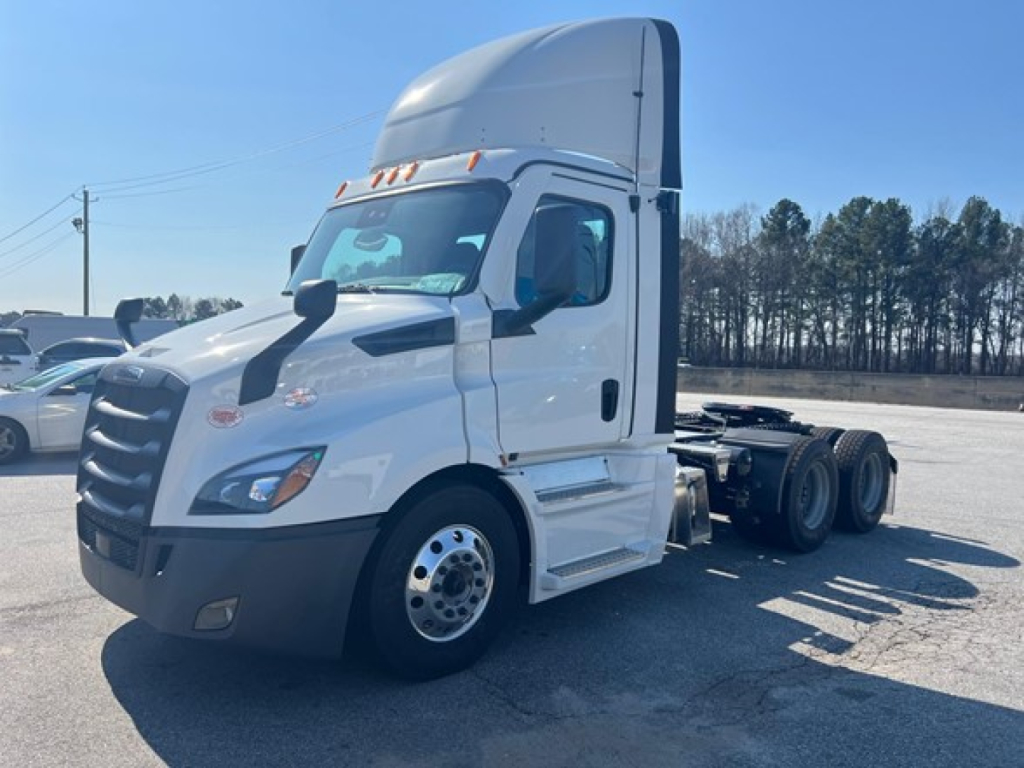 Truck cab front-left view of a white 2026 Freightliner Cascadia 116 day cab with high roof, three-quarter view, showing front bumper, grille, and dual rear axles.