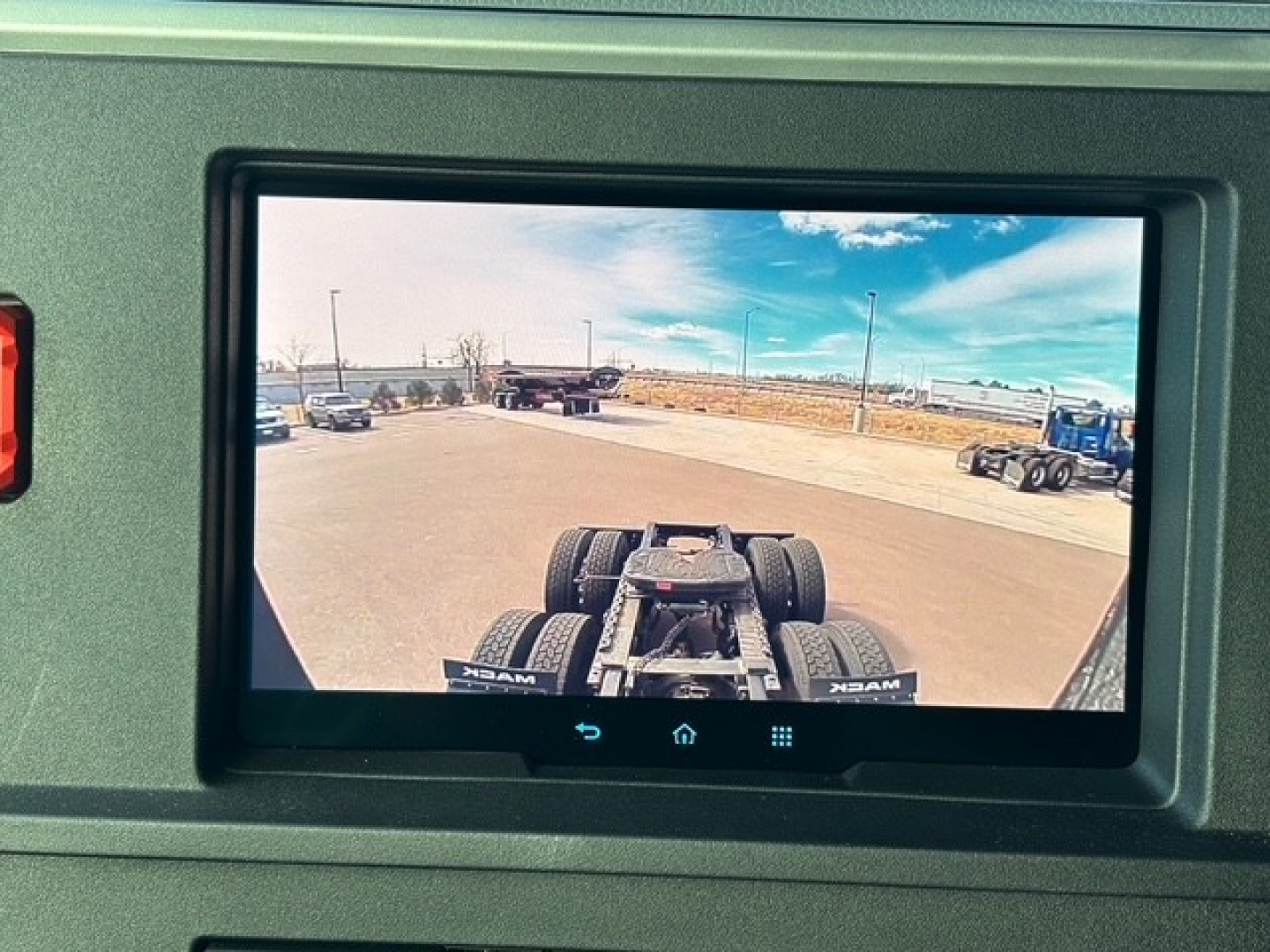 Truck cab/tractor rear view showing chassis frame and dual rear axles in the field.