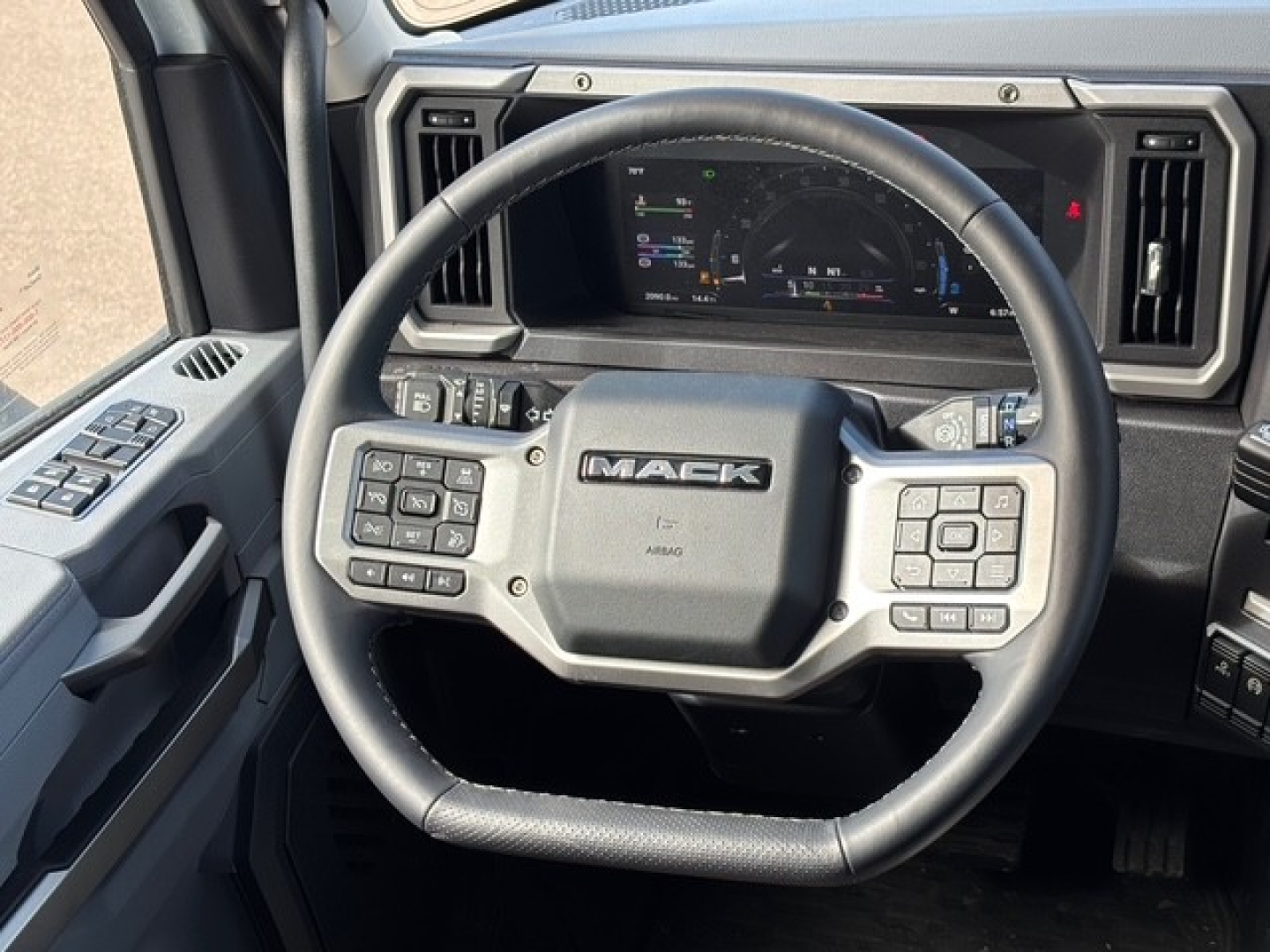Mack PR64T76H steering wheel and dashboard view showing multi-function controls and instrument cluster in a truck cab.