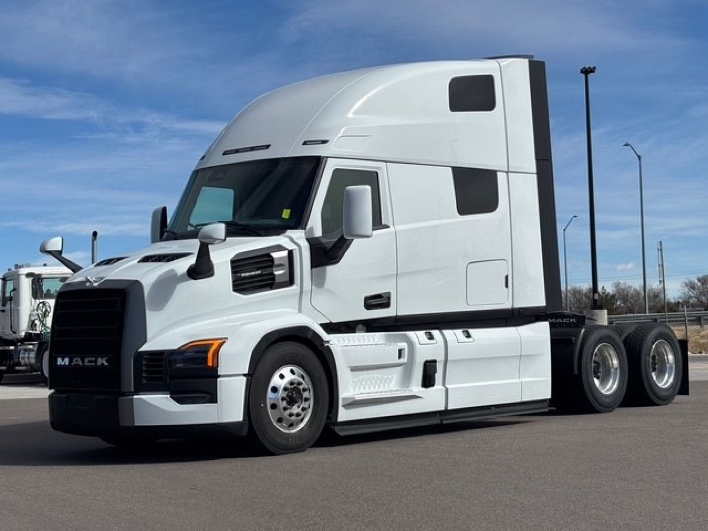 Mack PR64T76H tractor-trailer in white, side view showing cab with sleeper, front grille, and dual rear axles.