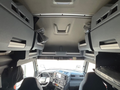 Truck cab interior view from rear looking forward showing overhead sleeper cabinets and dashboard; no legible serials or model text visible.