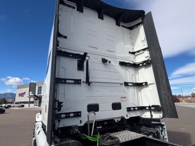 Mack PR64T76H cab interior showing rear tractor sleeper area with white metal walls, black hinges, and a folded tarp/curtain at the back.