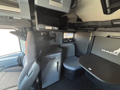 Cab interior of a 2026 Mack PR64T76H tractor showing sleeper area with table, storage, and overhead compartments.