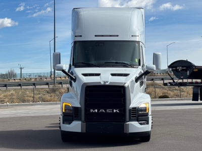 Truck front view showing Mack PR64T76H with large black grille, white cab, and daytime running lights.
