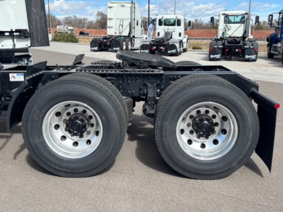 Mack PR64T76H tractor rear axle dual wheels showing tandem axle configuration and fuel/air lines; chassis frame and suspension visible; site lot in background.
