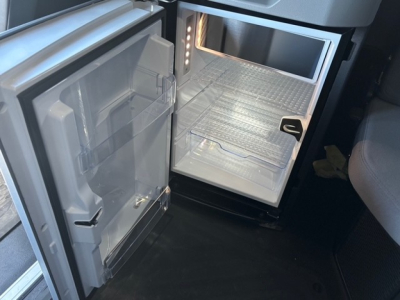 Mack PR64T76H truck cab interior showing open refrigerator/freezer unit and empty storage shelves in the sleeper area.