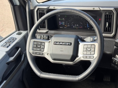 Mack PR64T76H steering wheel and dashboard view showing multi-function controls and instrument cluster in a truck cab.