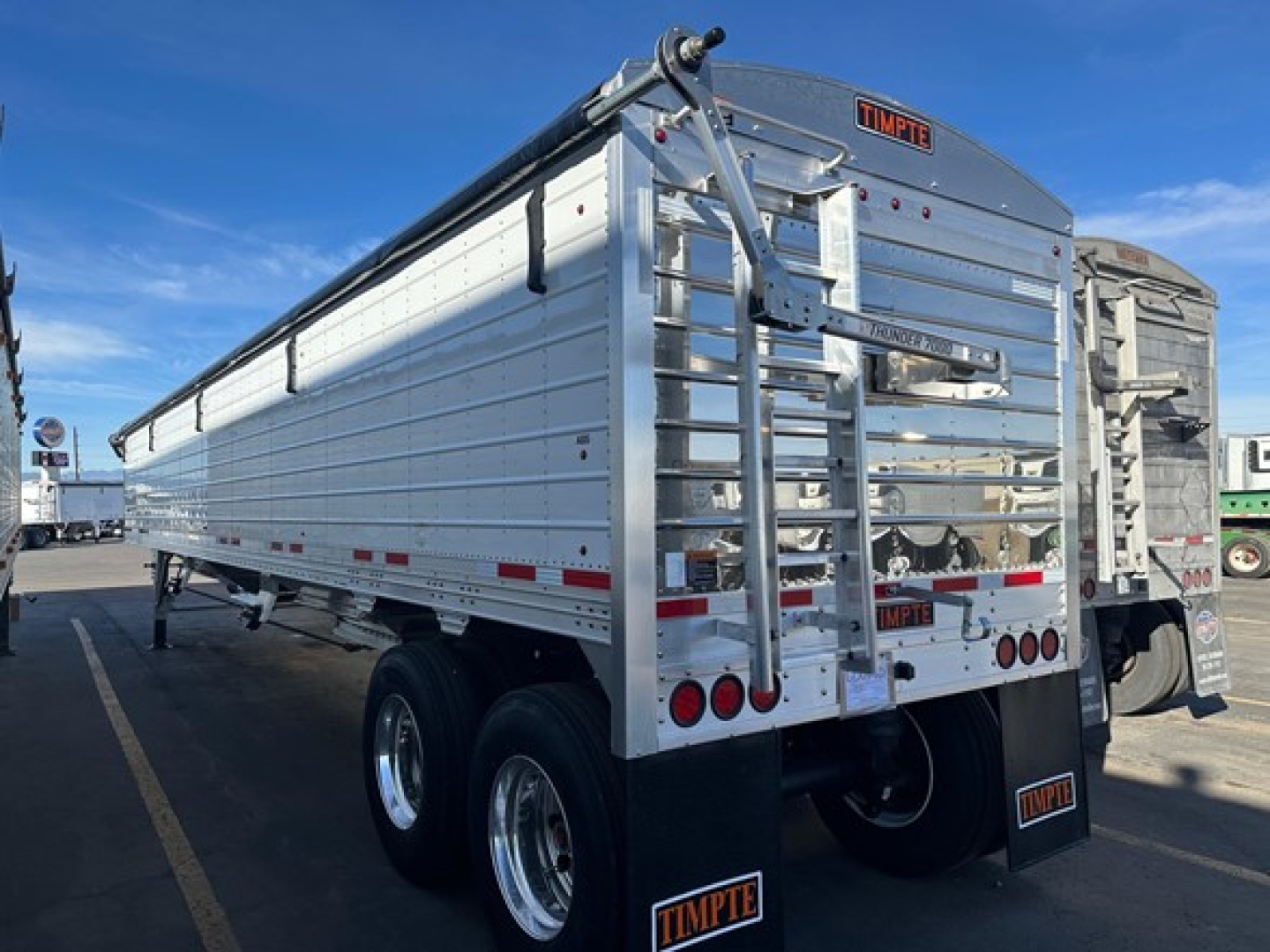 Timpte Super Hopper trailer showing aluminum corrugated body, rear swing-out doors, dual rear axles with chrome wheels, and Timpté branding.