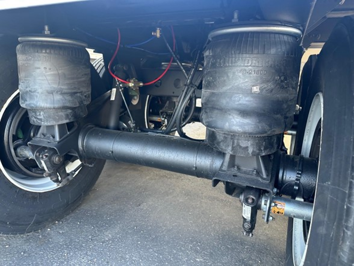Timpte hopper trailer undercarriage showing dual air springs, drive axle with differential housing, and horizontal steer/drive components; hoses and wiring visible.