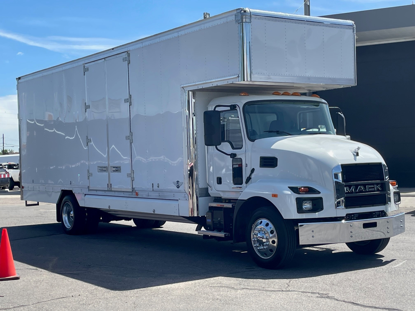 Truck side view of a new 2025 Mack MD6 box truck with a high-top cargo box and front chrome bumper, VIN 1M2MDBAA5SS016853 visible in listing details.