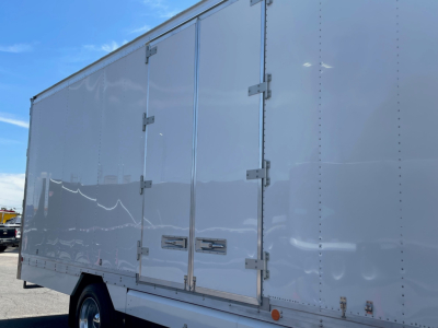 Box truck cargo area of a 2025 Mack MD6 trailer showing smooth white exterior with double rear doors and hinges.
