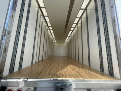 Box truck interior showing empty cargo space with wooden floor and side wall posts, viewed from rear doorway.