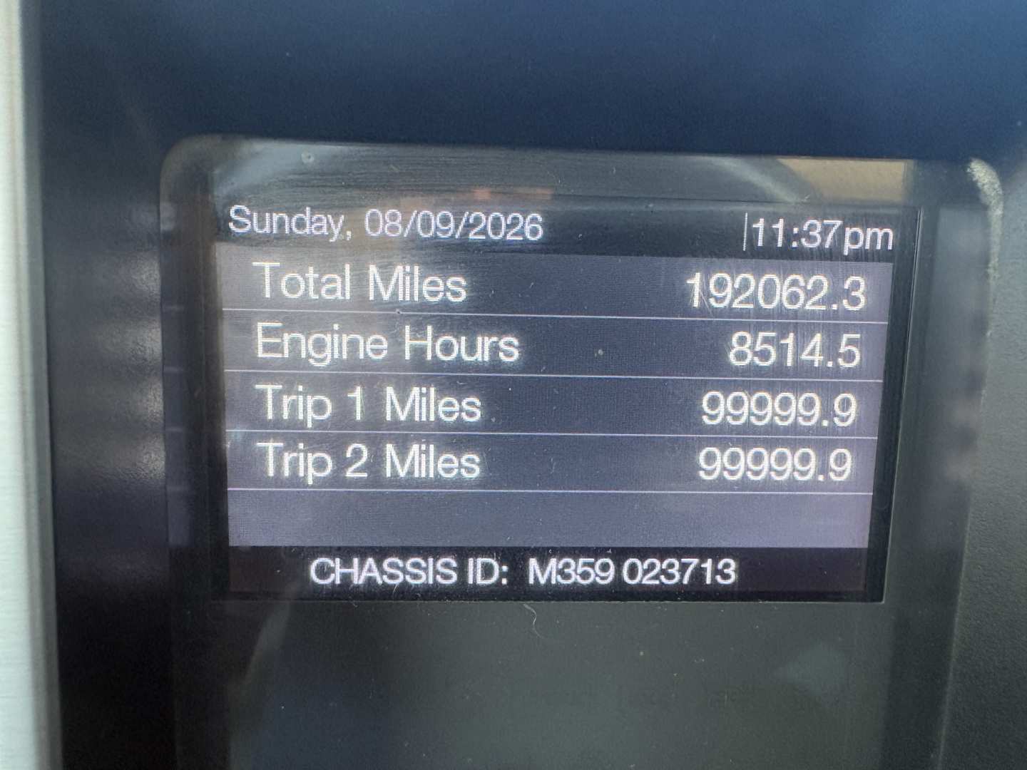 Dashboard screen showing vehicle data: Total Miles 192062.3, Engine Hours 8514.5, Trip 1 Miles 99999.9, Trip 2 Miles 99999.9, Date Sunday, 08/09/2026, CHASSIS ID M3589 023713