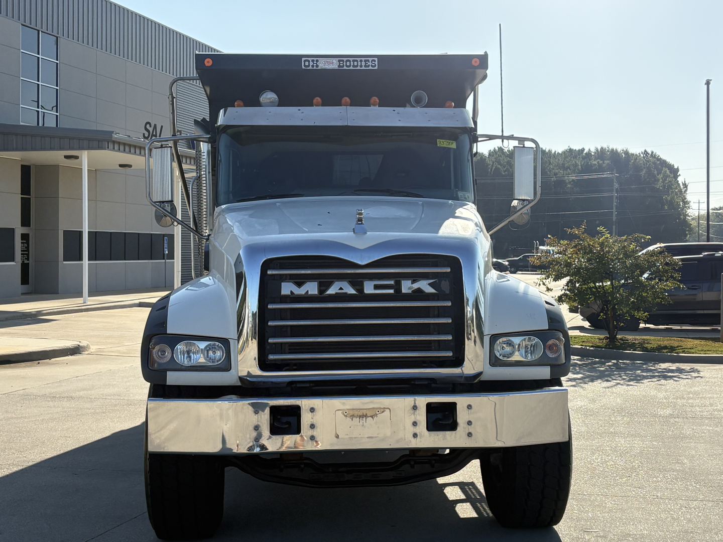 Mack GR64F dump truck front view showing bold grille with MACK letters, chrome bumper, large headlights, and raised dump bed visible at the top.
