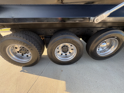 Three axles of a Mack GR64F dump truck showing wheels and tires under the dump bed.