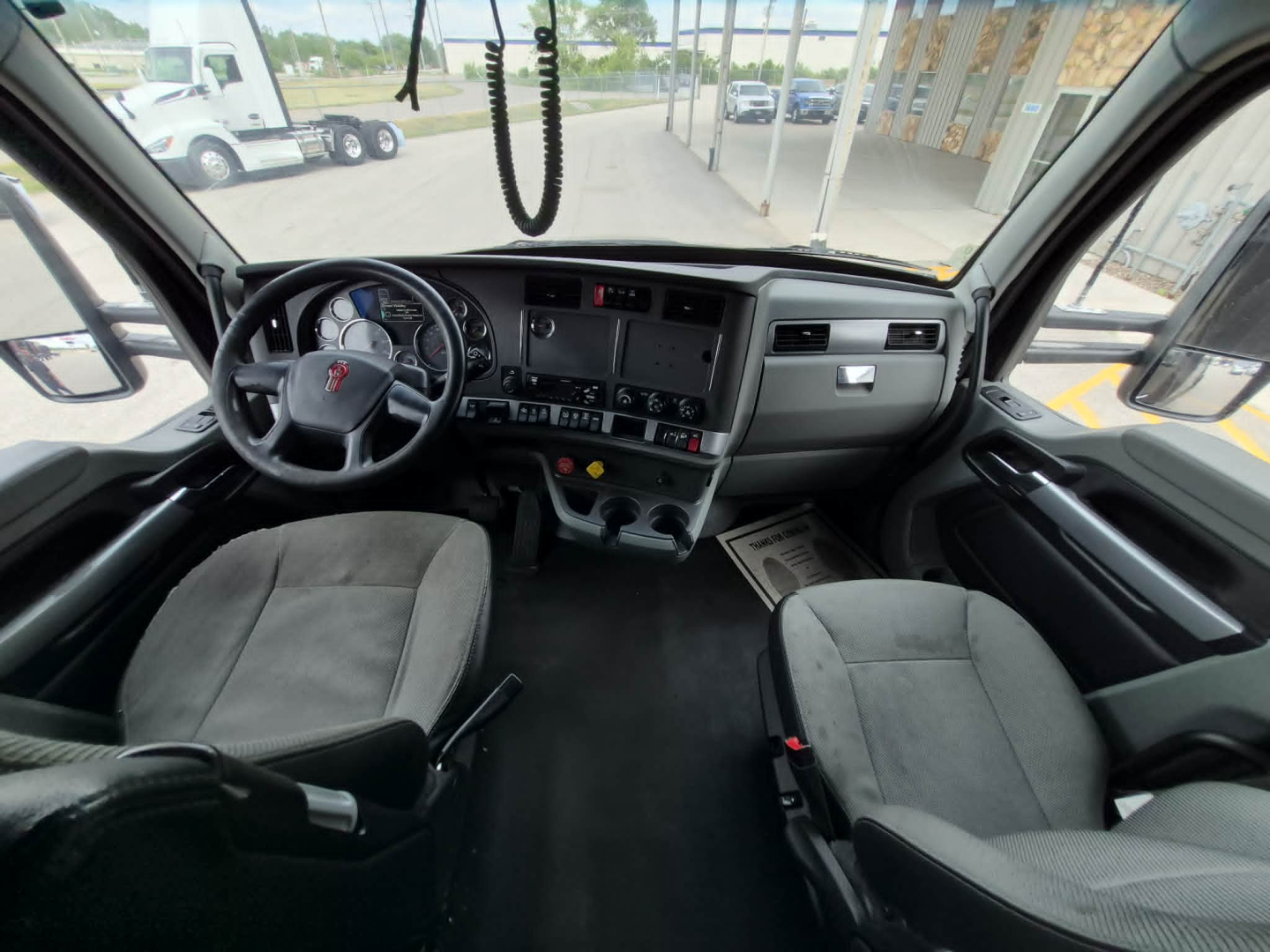 Kenworth T680 truck cab interior with steering wheel, dashboard, and two seats visible.