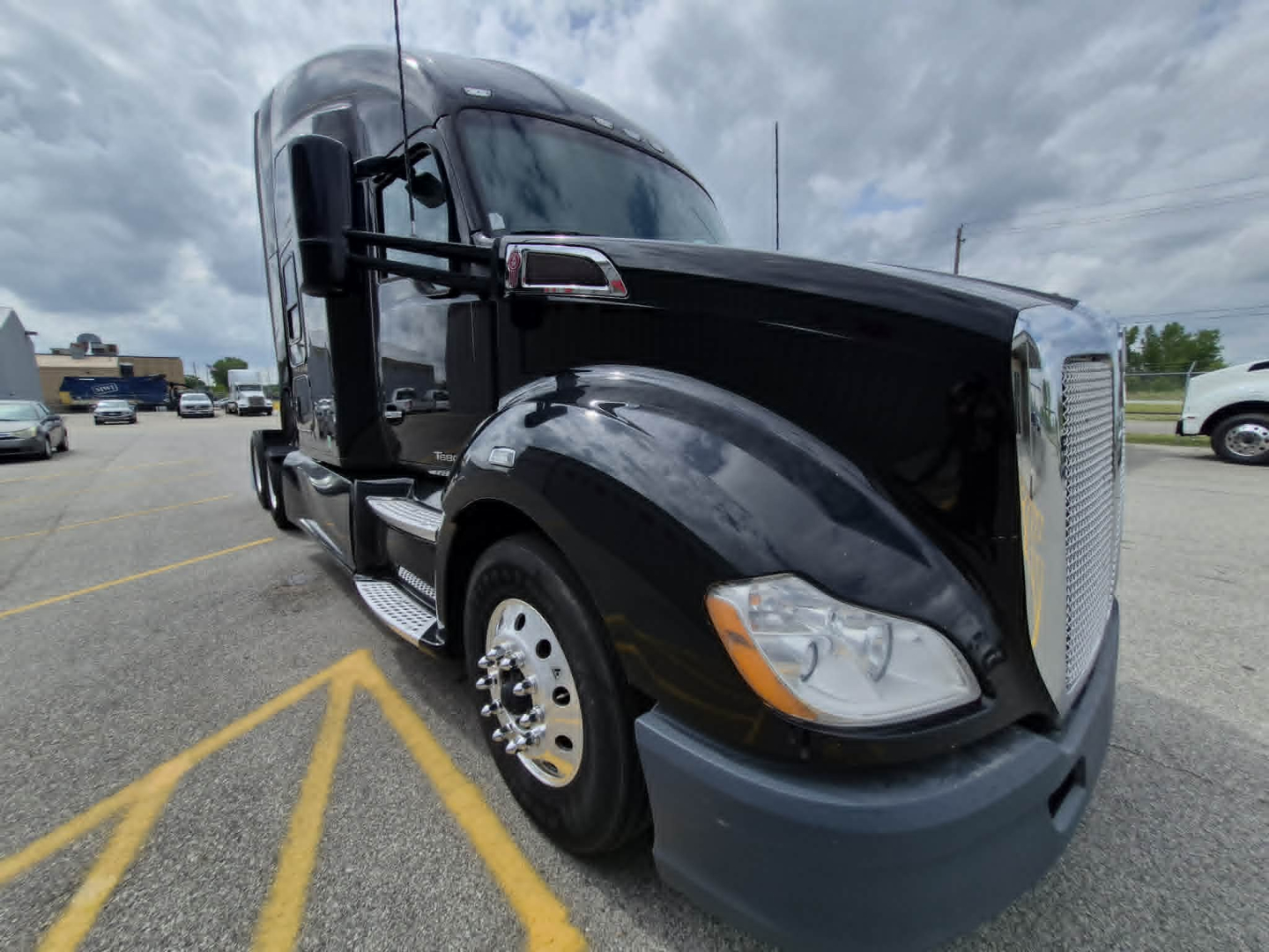 Kenworth T680 truck front-left view with black cab and chrome grille. No visible text on the image besides reflections.