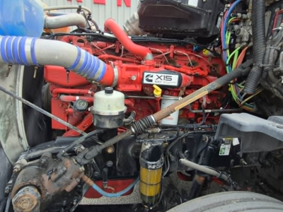 Kenworth engine bay with red engine block labeled X15 1000 series, yellow oil filter, various hoses, and wiring harnesses visible.