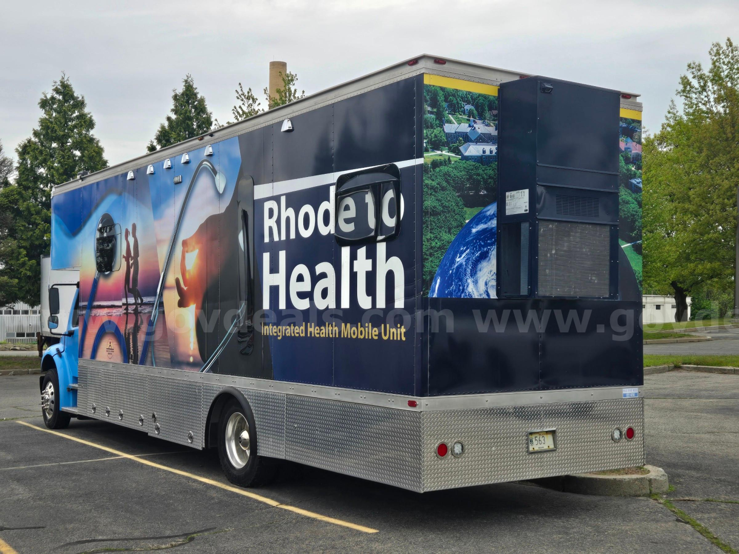 2019 Freightliner M2 box truck with Rhode Island Health integrated health mobile unit wrap, rear doors, high metal diamond-plate bumper, and rear lighting.