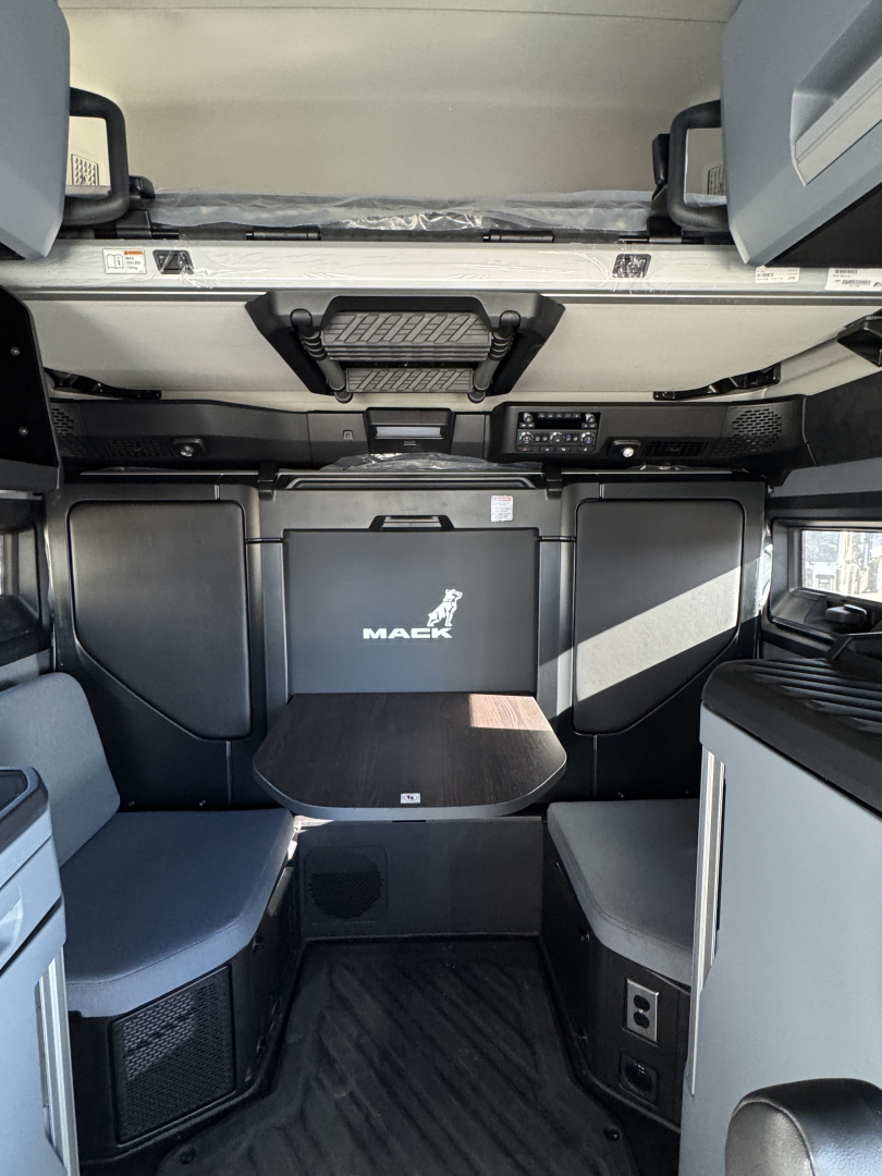 Mack PR64T76H interior cab view showing overhead storage compartments and driver seat area with Mack logo on the back panel.